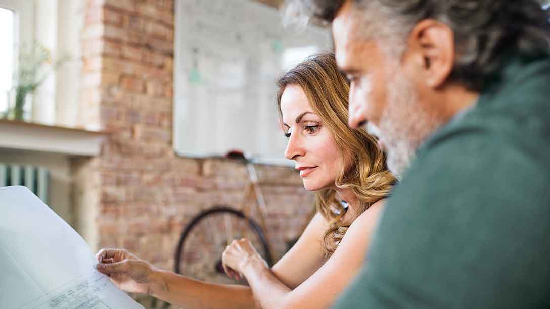 A man and woman at work look at an architect’s drawing